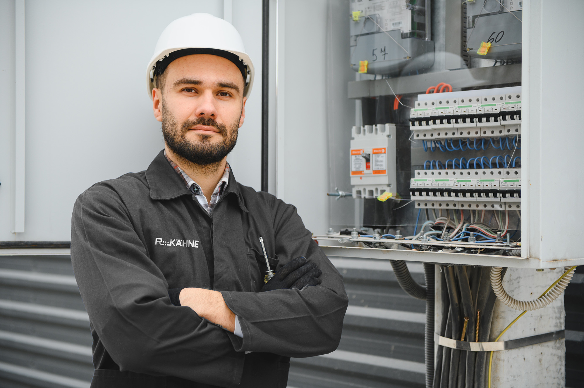 Elektriker vor offenem Schaltschrank bei Elektroinstallation und Wartung