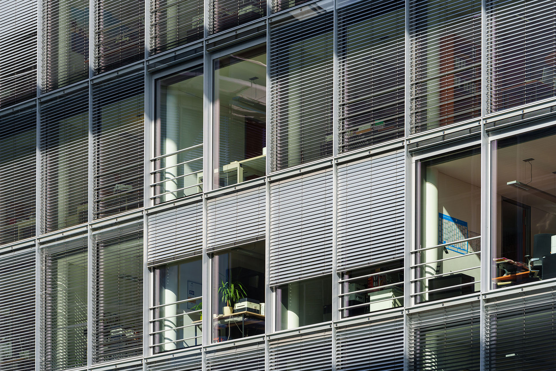 Moderne Bürofassade mit großen Fenstern und außenliegendem Sonnenschutz
